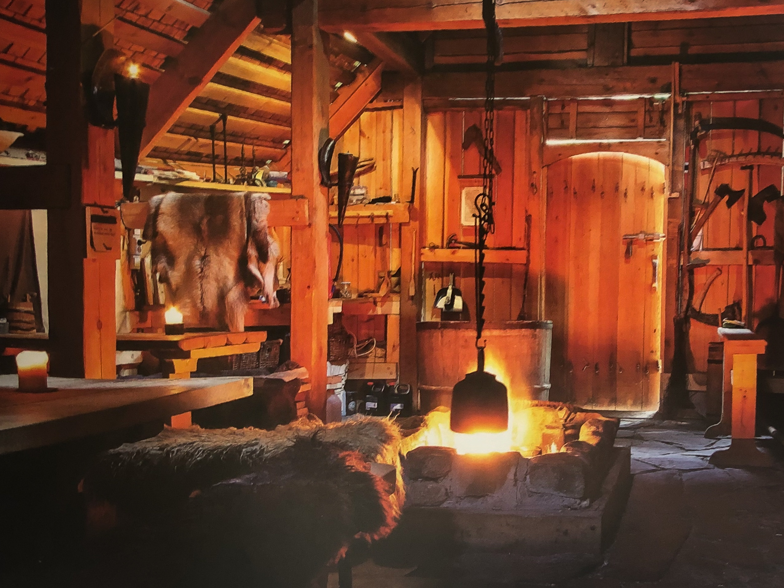 Cozy log-cabin workshop with wooden beams, tools hanging, and a glowing fire pit on a stone floor.